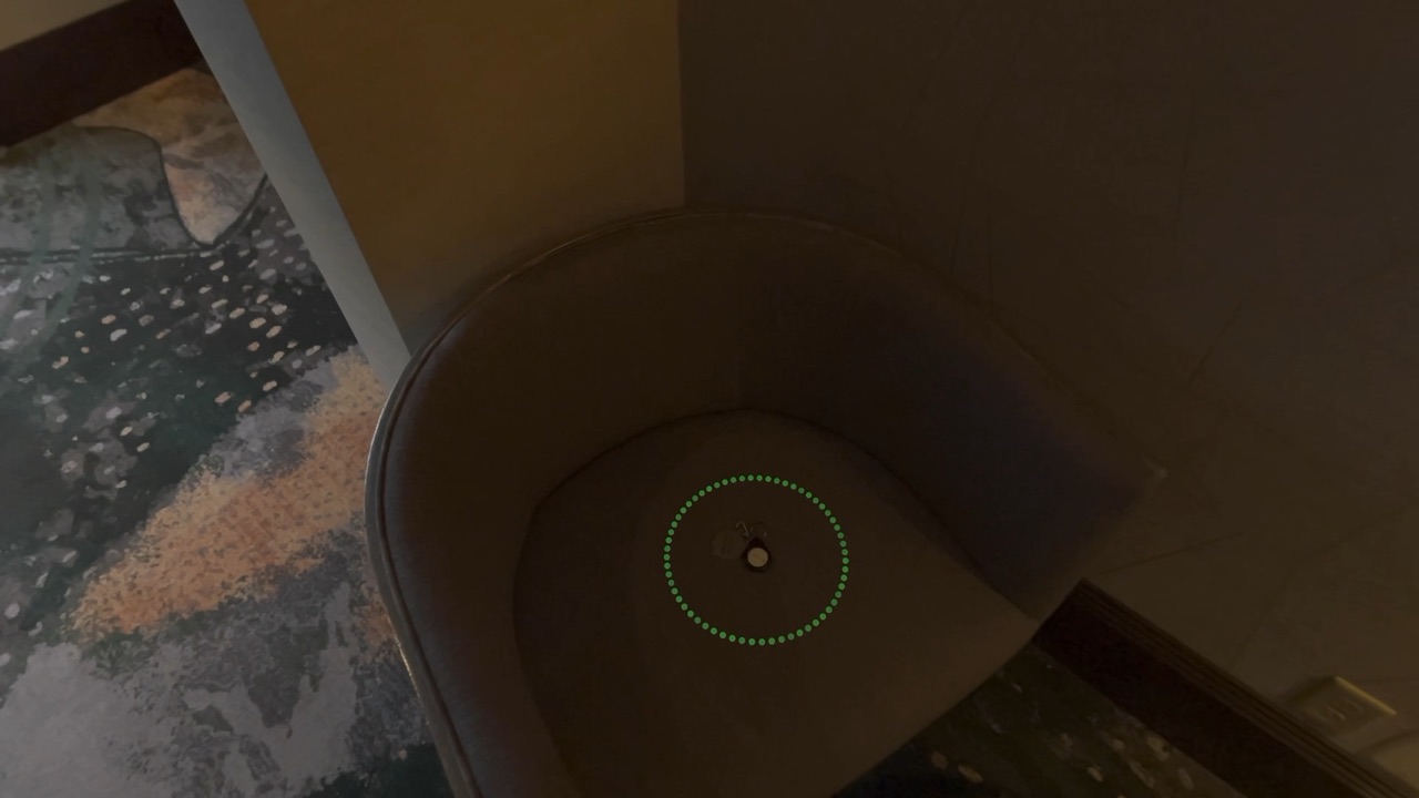 A small green ring of dots around the AirTag on the chair