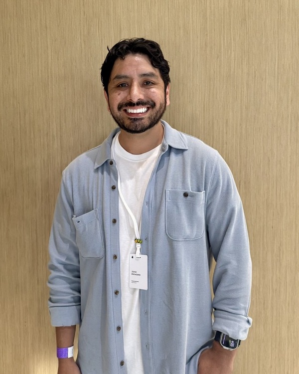 Jimmy Balladares smiling, wearing a light blue shirt over a white tee